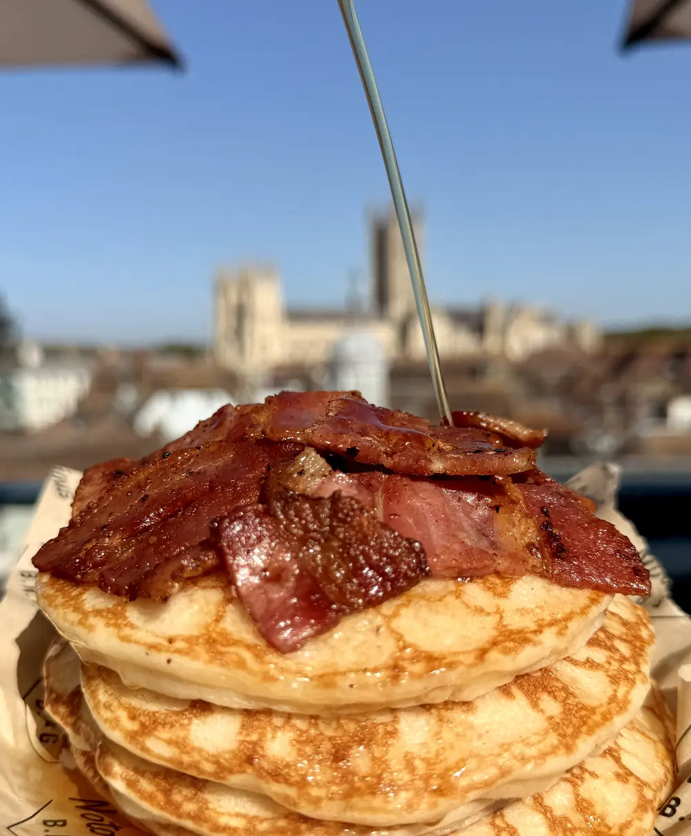 Syrup poured over a bacon pancake stack, Canterbury Cathedral behind