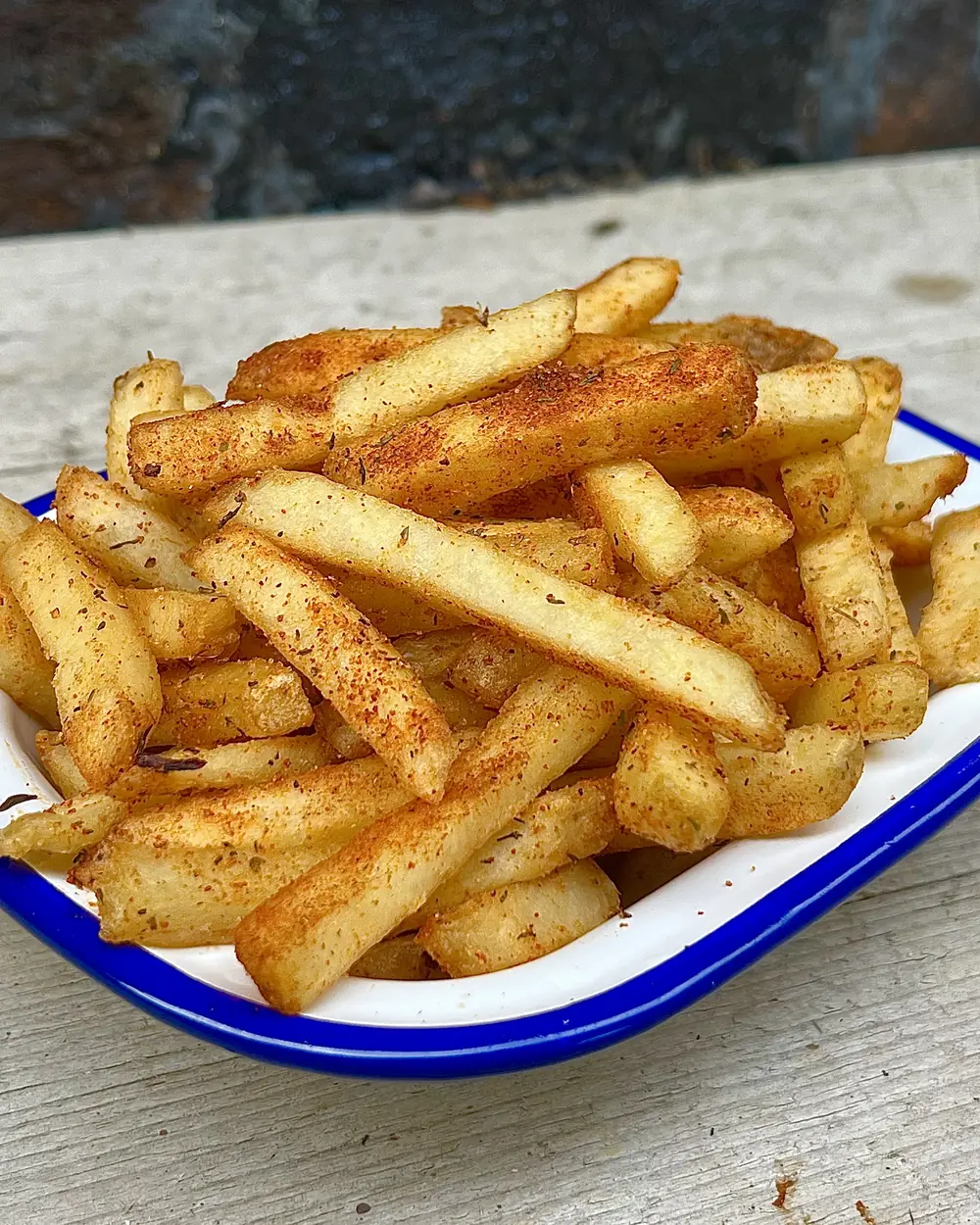 Cajun-seasoned skin-on fries in an enamel dish